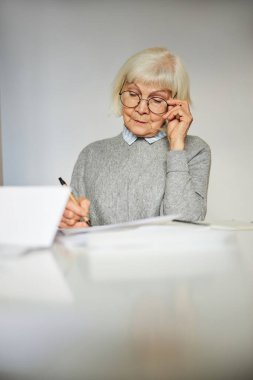 Masadaki belgelere bakan konsantre bir kadın.