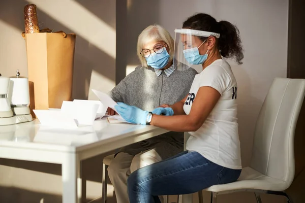 Két nő orvosi maszkban dokumentumokat vizsgál. — Stock Fotó