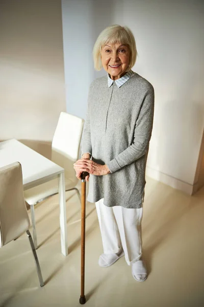 Senhora idosa alegre com uma bengala olhando para a frente — Fotografia de Stock