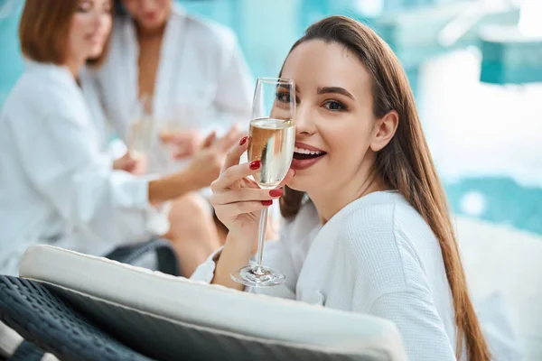 Happy young woman posing with champagne glass by the pool — Stock Photo, Image