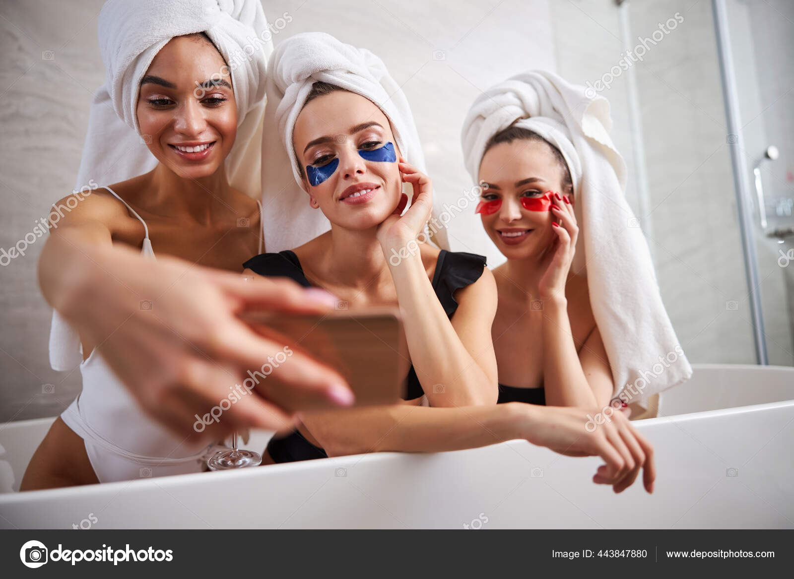Tres mujeres jóvenes sonriendo mientras toman fotos en una bañera