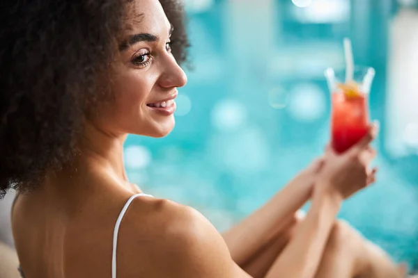 Relajada dama afroamericana tomando un delicioso cóctel cerca de la piscina —  Fotos de Stock