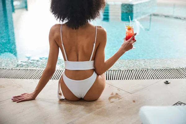 Joven dama afroamericana disfrutando de la piscina y beber cóctel — Foto de Stock