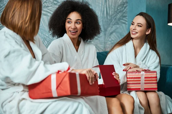 Mujer joven expresiva y sus amigos sosteniendo cajas de regalo rojas — Foto de Stock