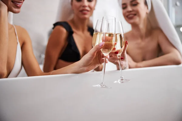 Las mujeres jóvenes ríen y beben champán sentado en la bañera —  Fotos de Stock