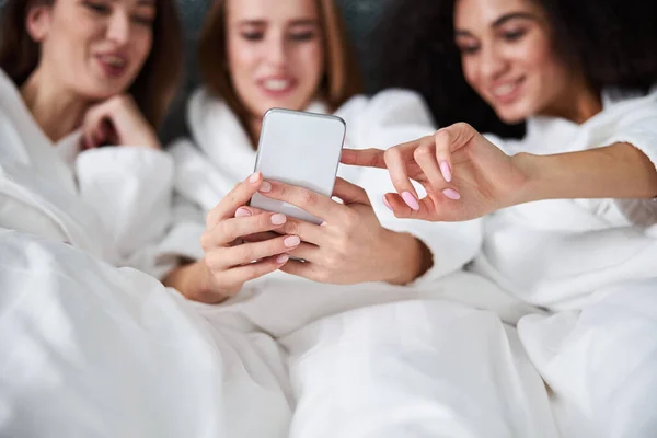Tre gioiose giovani donne che guardano e puntano lo schermo dello smartphone — Foto Stock