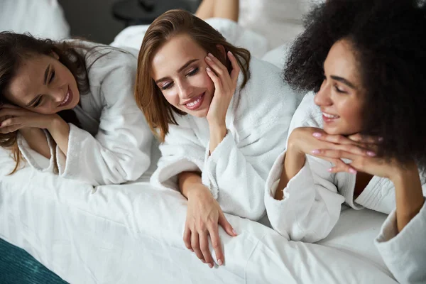 Tres mejores amigos disfrutando de relajarse en la cama del hotel —  Fotos de Stock