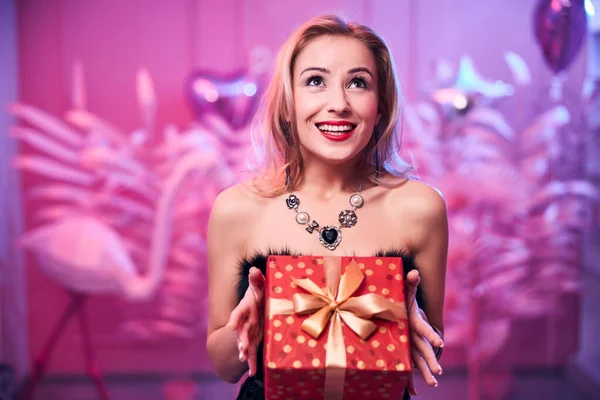 Joyous elegant woman holding a gift with both hands — Stock Photo, Image