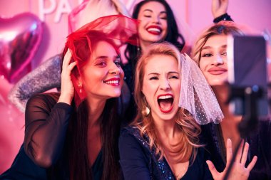 Cep telefonu kamerasına poz veren beş kadın.