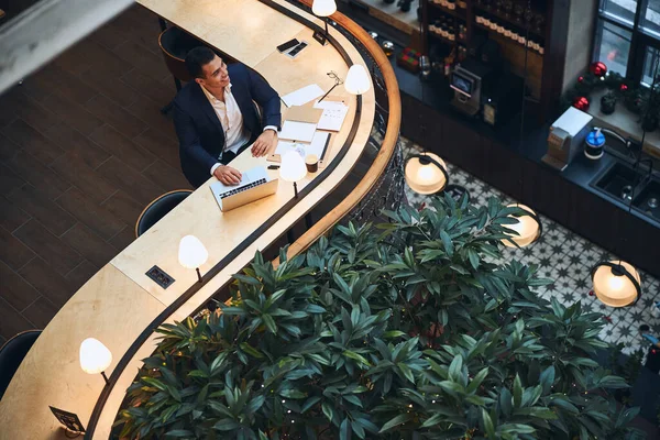 Joyful entrepreneur seated at the table looking away — Stock Photo, Image