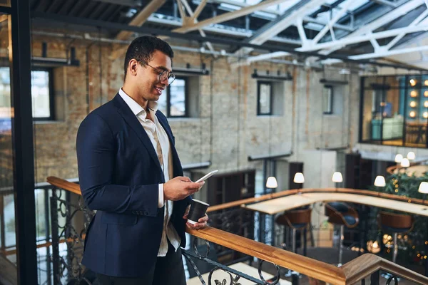 Tevreden donkerharige man die een sms leest — Stockfoto