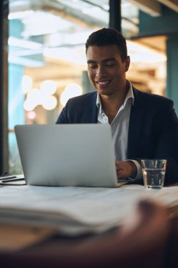 Bilgisayarında yazı yazan koyu renk saçlı memnun bir çalışan.