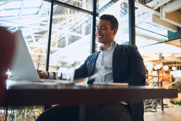 Vrolijke elegante werknemer zit aan de laptop — Stockfoto