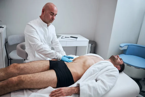 Especialista careca examinando paciente masculino no escritório — Fotografia de Stock