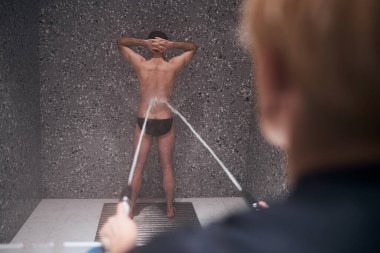 Woman doing Charcot douche service for man