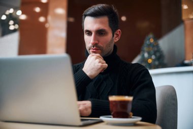 İş adamı Noel arifesini dizüstü bilgisayarla otelde geçiriyor.