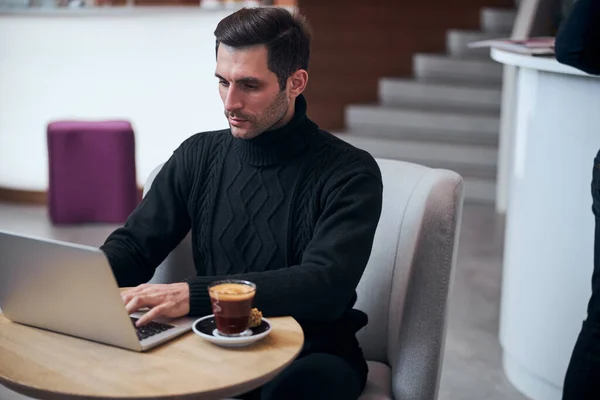 Hombre de negocios guapo que trabaja en línea en el ordenador portátil en la cafetería —  Fotos de Stock