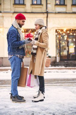 Mutlu genç bir kadın dışarıda erkek arkadaşından hediye alıyor.
