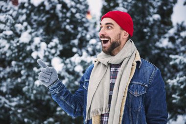 Neşeli genç erkek kış ormanında eğleniyor.