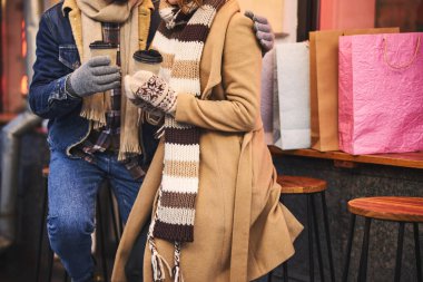 Bir kadın sokakta erkek arkadaşıyla çay içiyor.