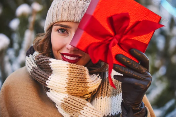 Gülümseyen güzel kadın Noel hediyesini açık havada tutuyor. — Stok fotoğraf