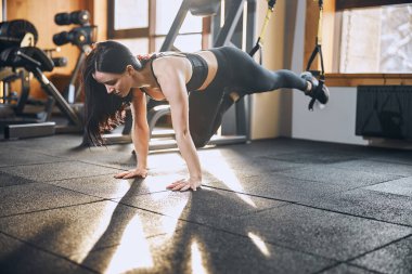 Spor salonunda antrenman yapan genç ve mutlu bir kadın.