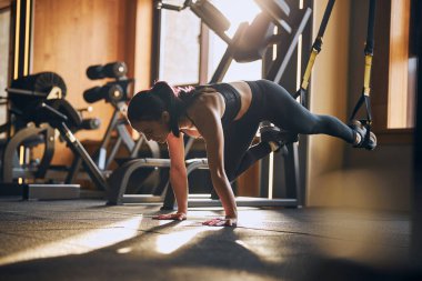 Sportif kadın direnç kemerleriyle vücut çalışıyor.