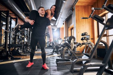 Beden dersinde kız arkadaşını omuzlarında tutan mutlu genç adam.