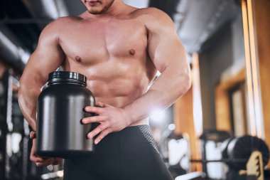 Güçlü sporcu spor salonunda protein alıyor.