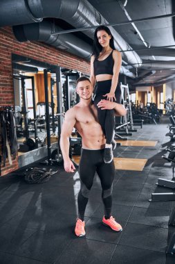 Spor salonunda birlikte egzersiz yapan neşeli genç çift.