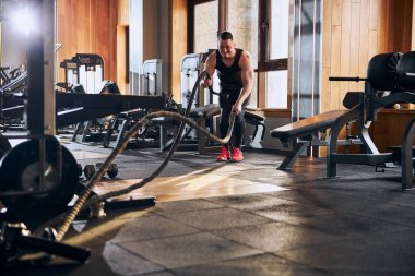 Güçlü genç adam jimnastik salonunda vücut çalışıyor.