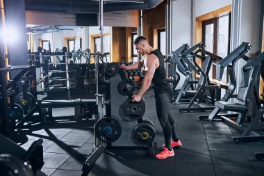 Spor salonunda ağır sıkletlerle vücut geliştirme eğitimi alan genç biri.