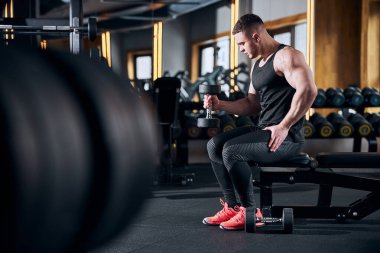 Spor salonunda pazı egzersizi yapan atletik bir genç.