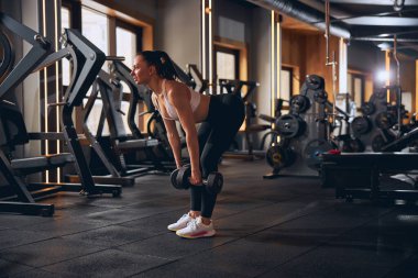 Dambıllarla çalışan motive olmuş zayıf kadın.