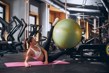 Neşeli genç bir kadın. Kıyafetlerle karın kasları çalışıyor.