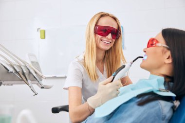 Yetenekli genç stomatolog hastasıyla çalışıyor.