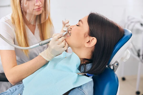 Joven estomatólogo competente haciendo procedimiento de cuidado dental — Foto de Stock