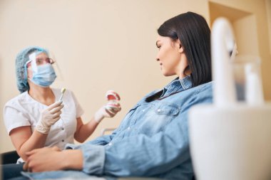 Genç esmer kadın aile stomatoloğunu dinliyor.