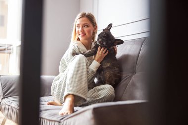 Kanepede evcil hayvanını kucaklayan genç bir bayan.