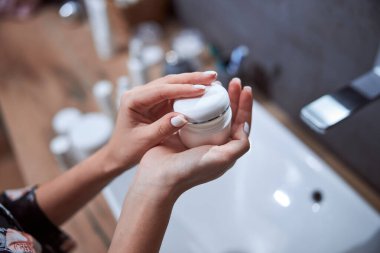 Kadın kepiyle krema kutusunu kapatıyor.