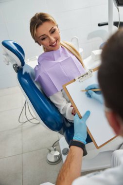 Mutlu kadın dişçiye diş sorunlarını anlatıyor.