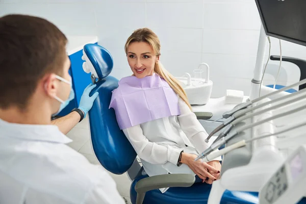 Mujer en silla dental preguntando a su médico — Foto de Stock