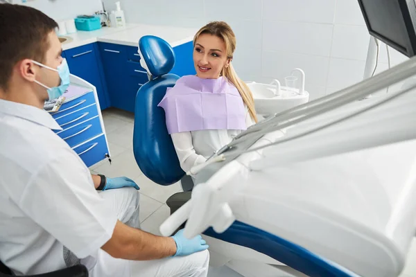Dentista está sentado cerca de su paciente femenino — Foto de Stock
