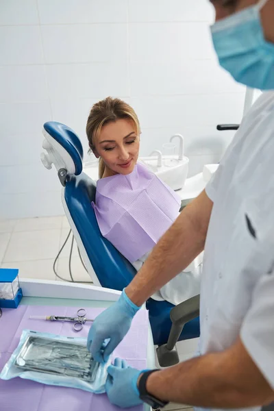 Mujer mirando fijamente al dentista abriendo la bolsa de instrumentos — Foto de Stock