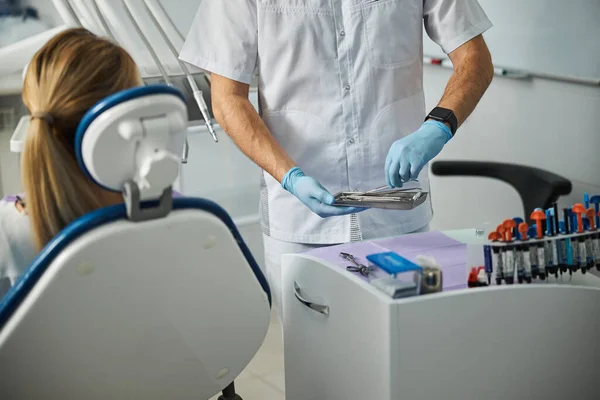 Médico especialista eligiendo pinzas dentales de una bandeja — Foto de Stock