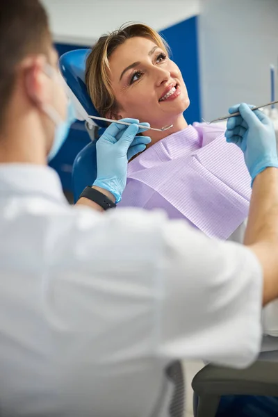 Dentista moviendo sonda dental y espejo a dientes de mujer — Foto de Stock