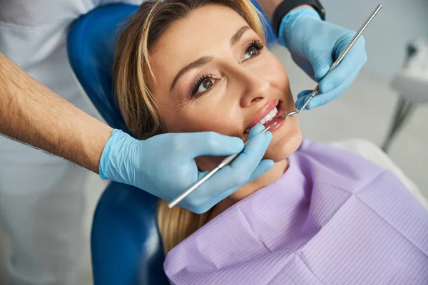 Dentista tocando los dientes del paciente con herramientas estomatológicas — Foto de Stock