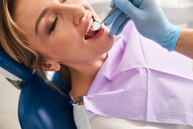 Dişlerinin aynayla incelenmesinden hoşlanan bir kadın