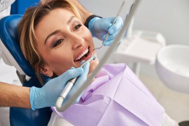 Heyecanlı güzel bayan diş delmeye hazırlanıyor.