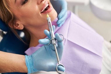 Kadın ağzına bir şırınga iğnesi sokuluyor.